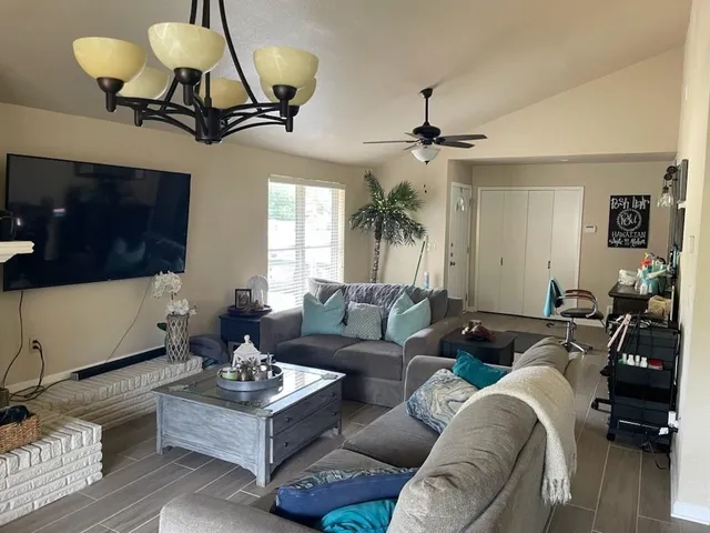 a living room with furniture a chandelier and a flat screen tv