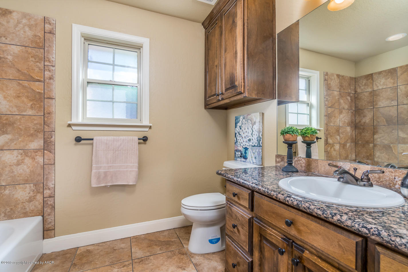 9203 Orry Avenue Amarillo, TX 79119 - Photo 16 of 22 a bathroom with a granite countertop sink a toilet and a mirror