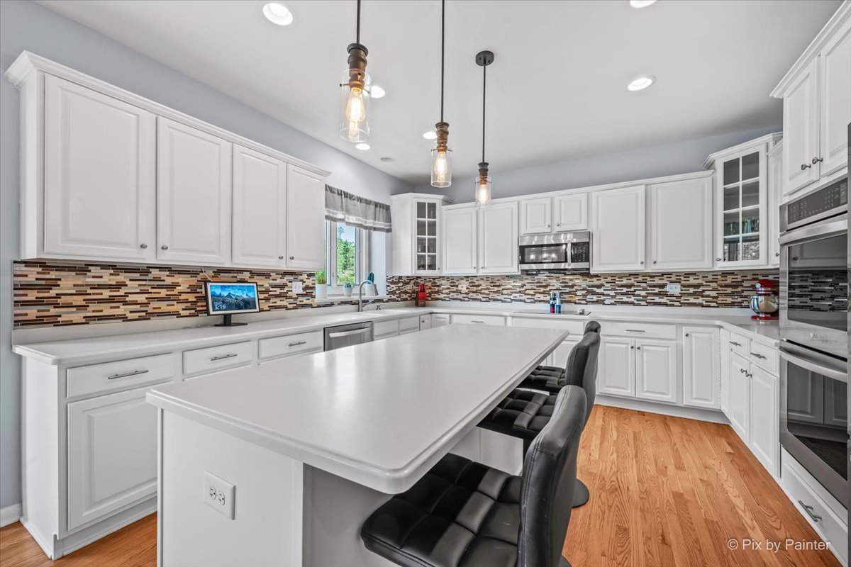 7104 Dove Way Cary, IL 60013 - Photo 20 of 82 a kitchen with stainless steel appliances granite countertop a stove a sink dishwasher a refrigerator and white cabinets with wooden floor