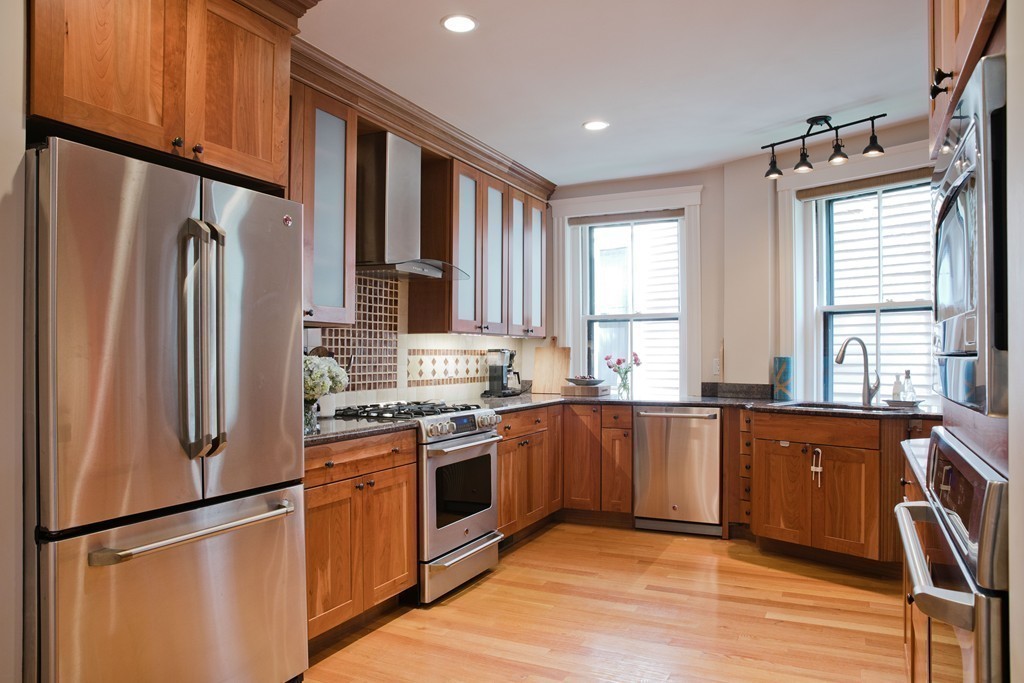 26 Hurlbut Street, Unit 2 Cambridge, MA 02138 - Photo 4 of 17 a kitchen with stainless steel appliances granite countertop a refrigerator a sink dishwasher a stove and white countertops with wooden floor
