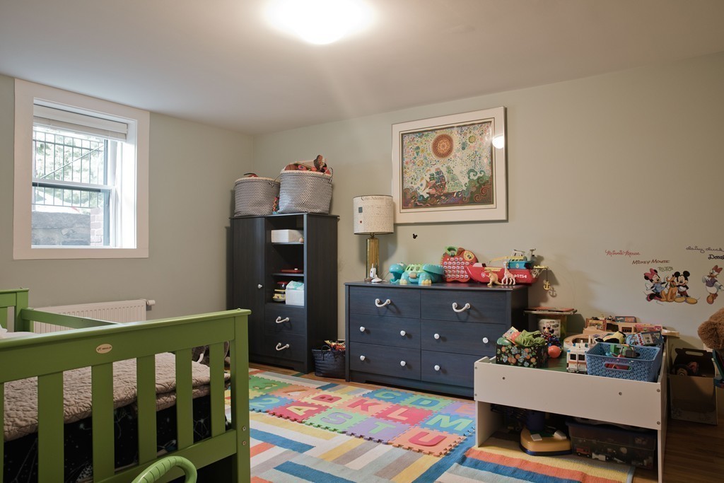 26 Hurlbut Street, Unit 2 Cambridge, MA 02138 - Photo 9 of 17 a bedroom with baby crib and wooden floor