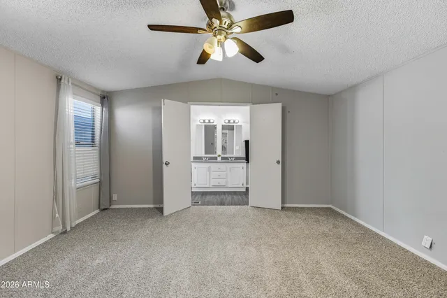 an empty room with chandelier fan and windows