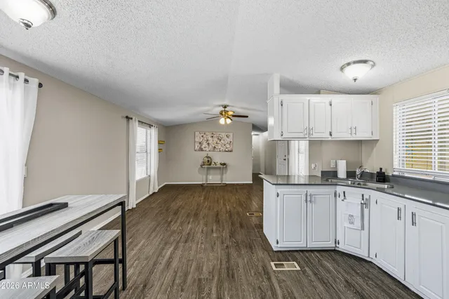 a kitchen with granite countertop a stove a sink and white cabinets with wooden floor