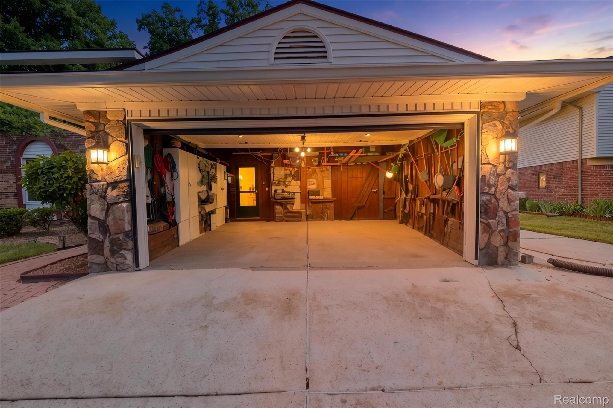 41768 Hanford Road Canton, MI 48187 - Photo 25 of 28 Garage with stone veneer columns, exterior lighting fixtures, and a concrete driveway