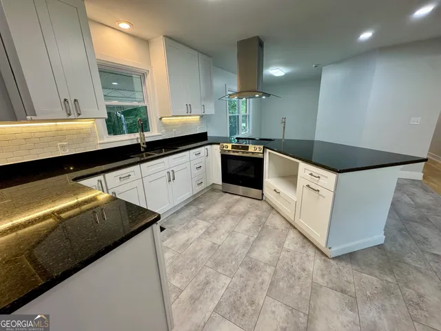 a kitchen with stainless steel appliances kitchen island granite countertop a sink and a stove
