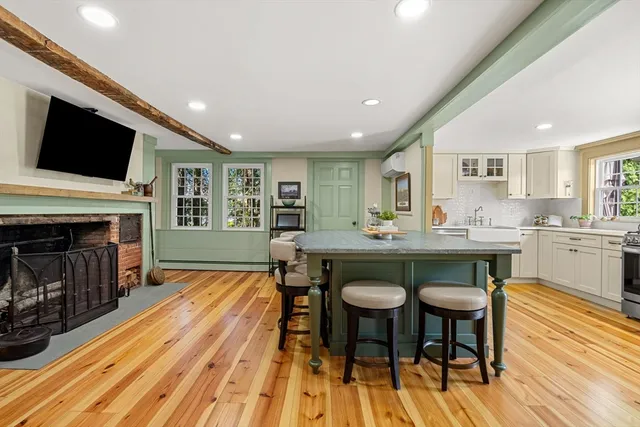 a living room with stainless steel appliances furniture a fireplace and a flat screen tv