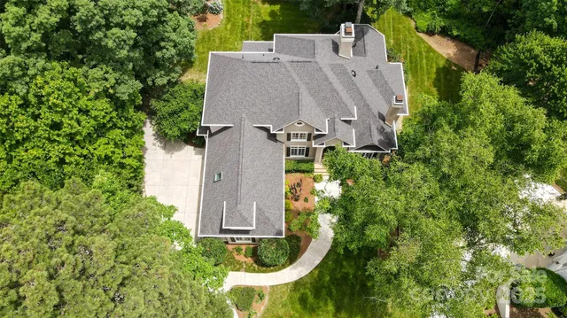 an aerial view of a house with garden space and trees all around