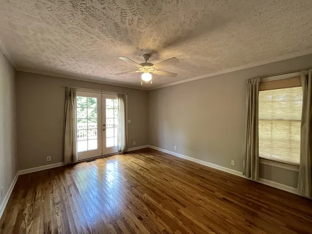 an empty room with wooden floor and windows