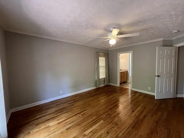 a view of an empty room with window and wooden floor