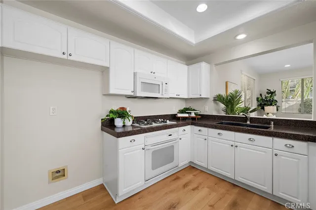 a kitchen with granite countertop white cabinets and white appliances