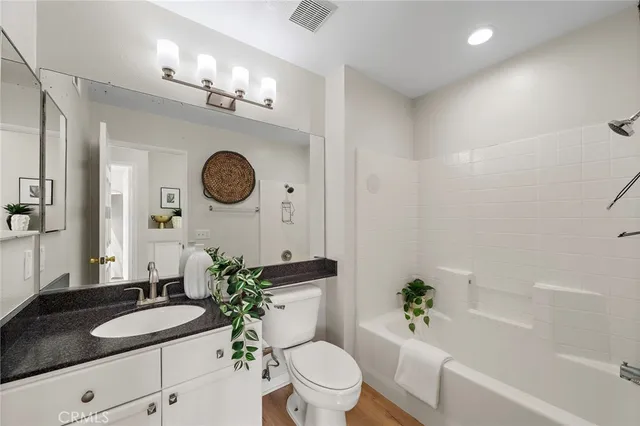 a bathroom with a granite countertop toilet a sink and a mirror