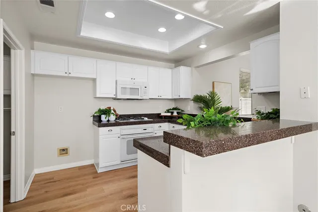 a kitchen with stainless steel appliances granite countertop a sink a stove a refrigerator and white cabinets
