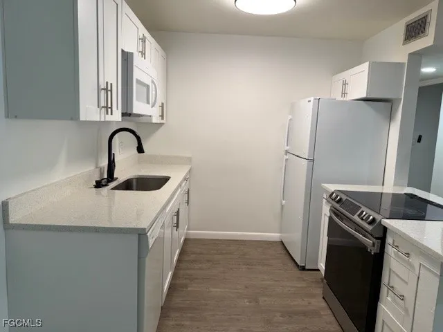 a kitchen with a sink a refrigerator and cabinets
