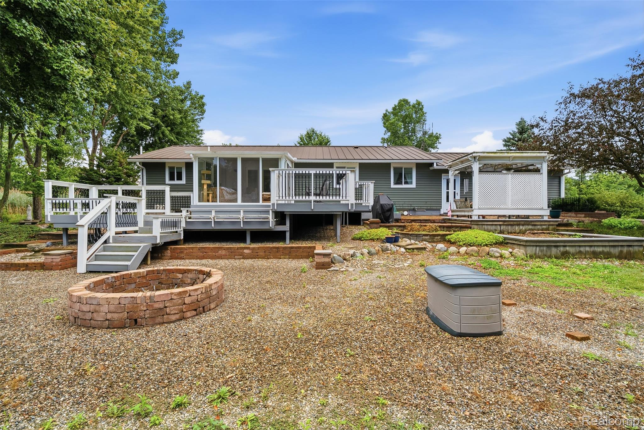 Rear exterior featuring a multi-level deck, enclosed porch, and a brick-built fire pit