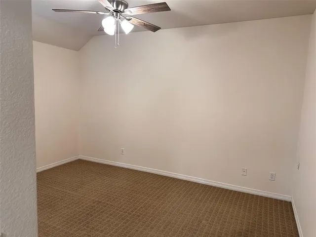 an empty room with a chandelier fan and windows