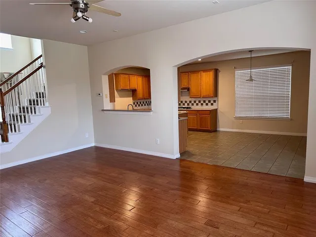 a view of an empty room with window and wooden floor