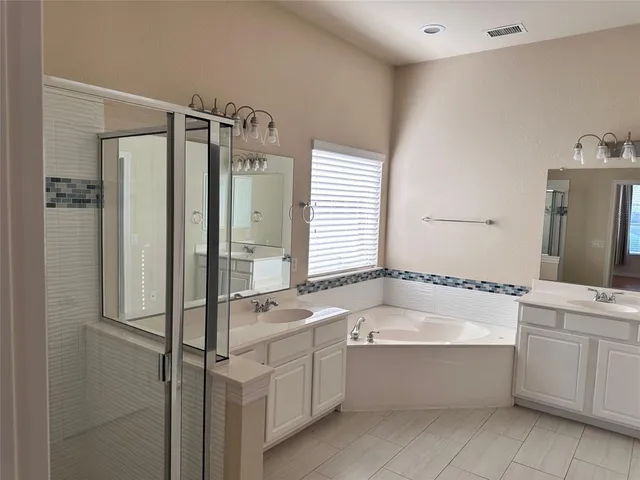 a bathroom with a tub sink shower and mirror