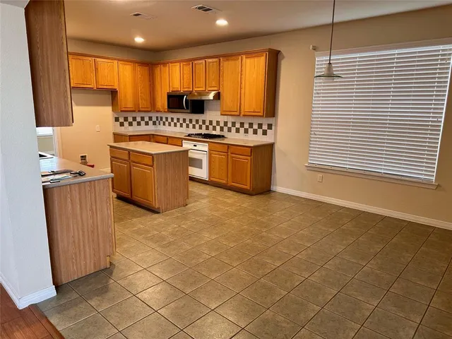 a kitchen with stainless steel appliances a sink a stove a refrigerator cabinets and a window