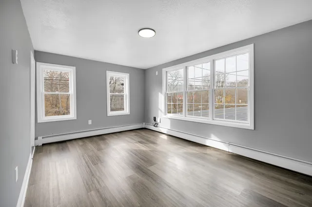 a view of an empty room with wooden floor and a window