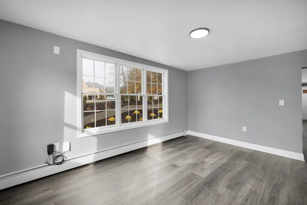 an empty room with wooden floor and windows