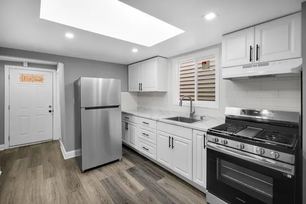 a kitchen with appliances a sink cabinets and wooden floor