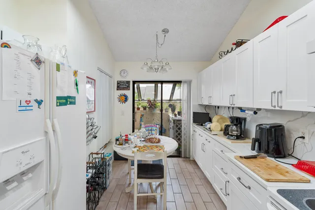 a kitchen with stainless steel appliances a refrigerator a sink dishwasher a stove a dining table and chairs with wooden floor