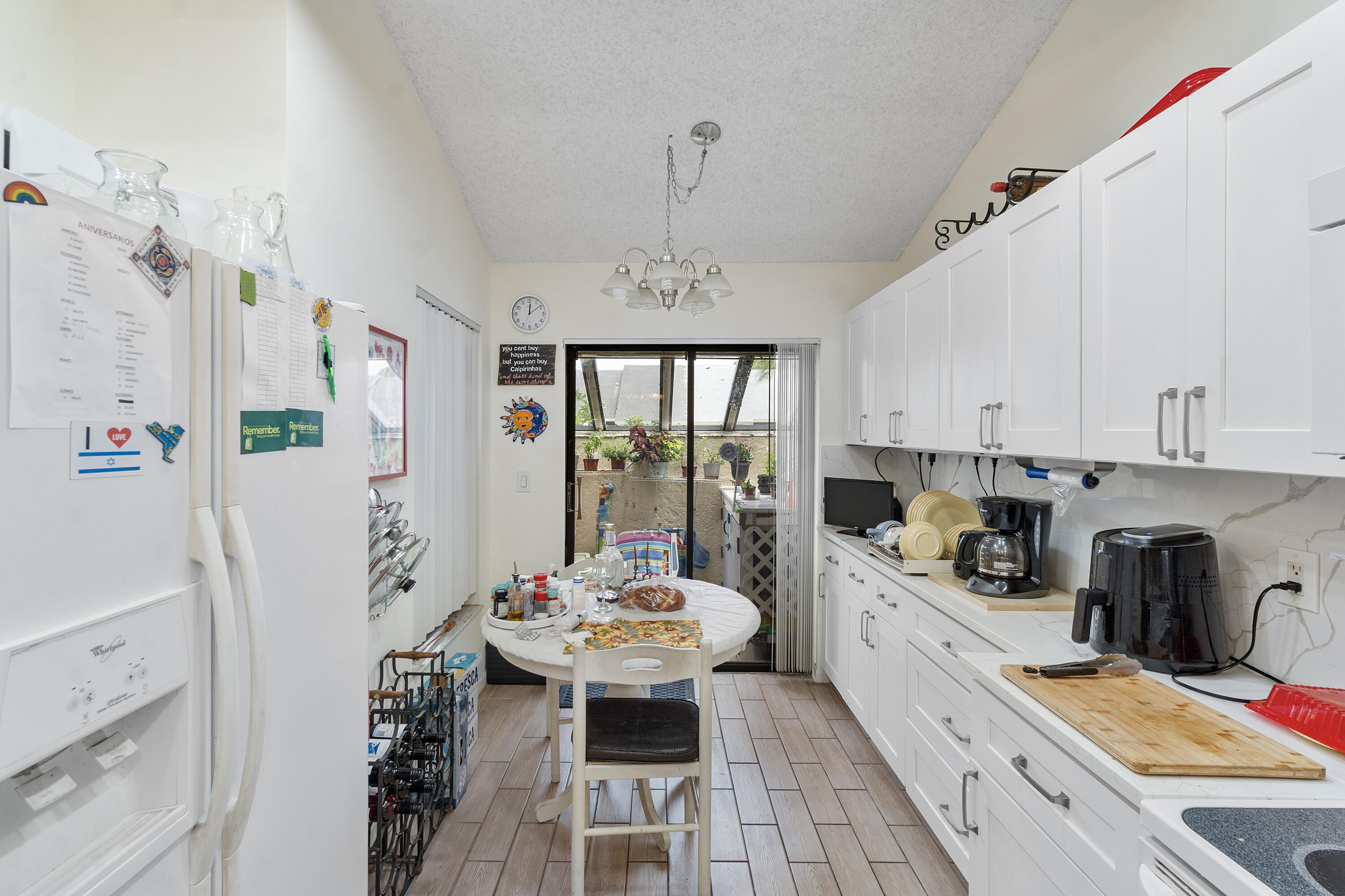 10900 Waterberry Court Boca Raton, FL 33498 - Photo 11 of 28 a kitchen with stainless steel appliances a refrigerator a sink dishwasher a stove a dining table and chairs with wooden floor