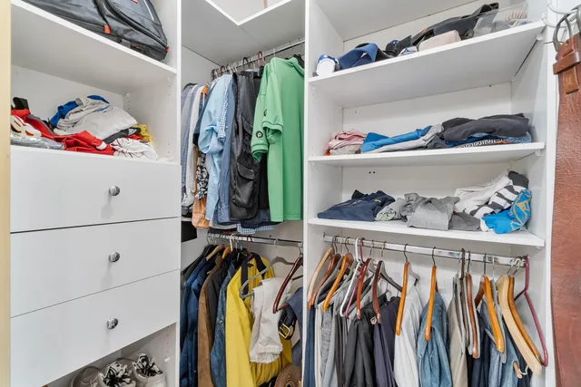a view of walk in closet with clothes and shoes