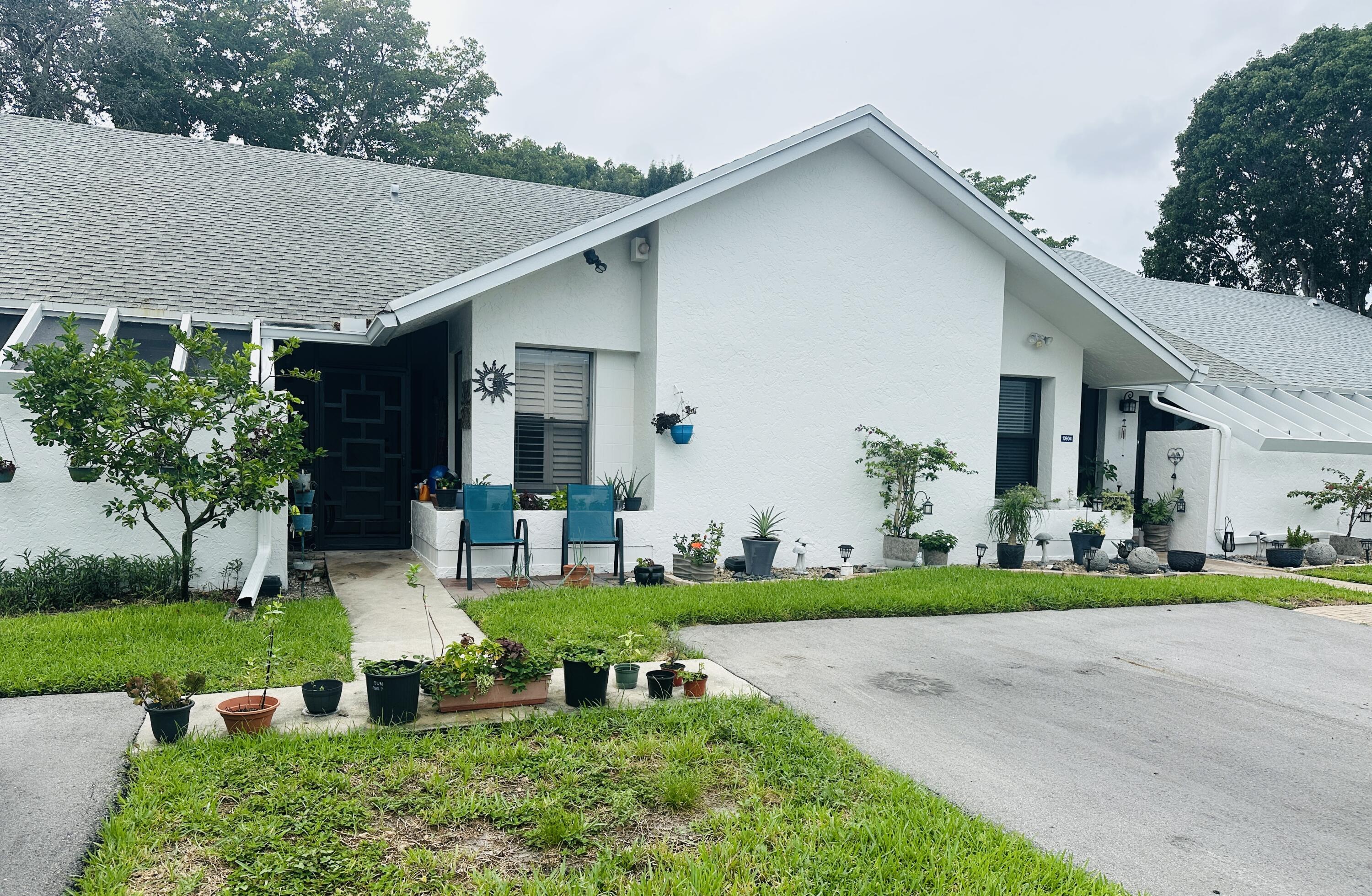 10900 Waterberry Court Boca Raton, FL 33498 - Photo 2 of 28 a front view of a house with a yard table and chairs