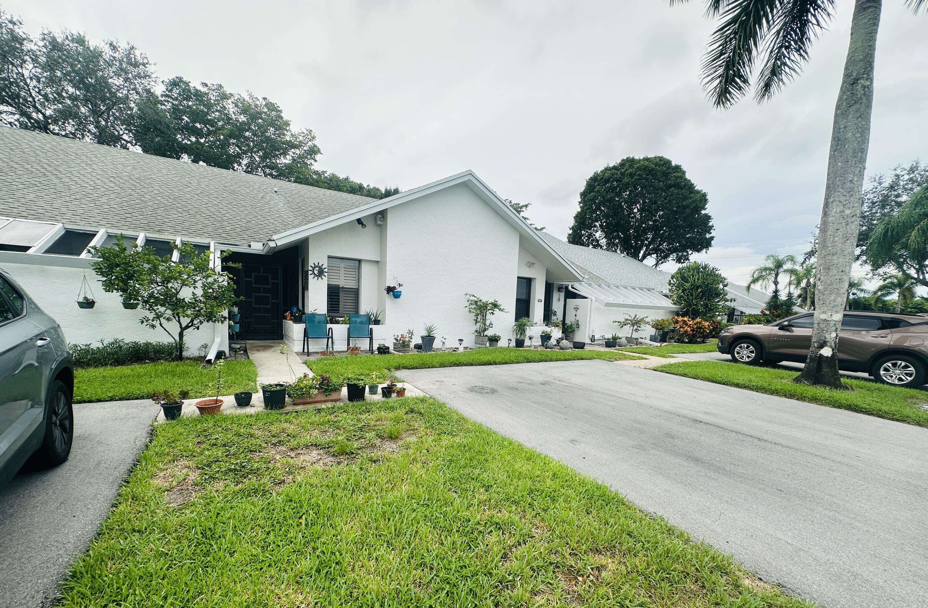 10900 Waterberry Court Boca Raton, FL 33498 - Photo 4 of 28 a view of a white house with a big yard and potted plants