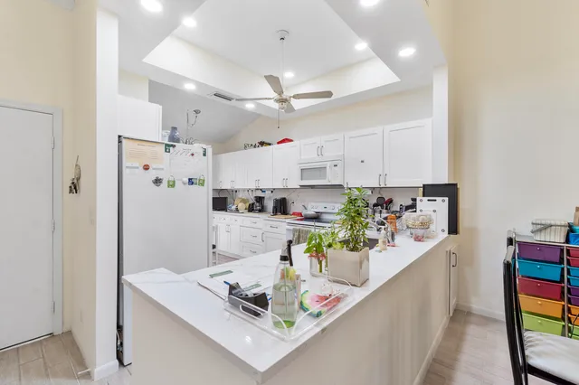 a kitchen with stainless steel appliances granite countertop a refrigerator a stove a sink dishwasher and white cabinets with wooden floor