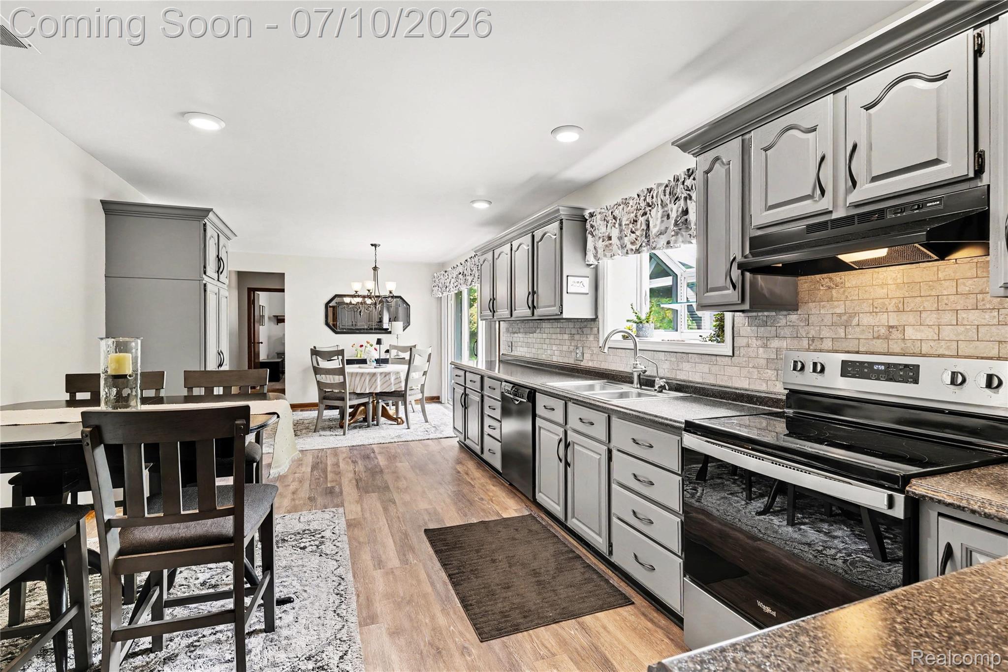 2180 Hurst Road St. Clair, MI 48079 - Photo 12 of 39 Contemporary kitchen featuring wood-finish flooring, gray cabinetry with black hardware, a light-toned brick-patterned backsplash, and recessed lighting