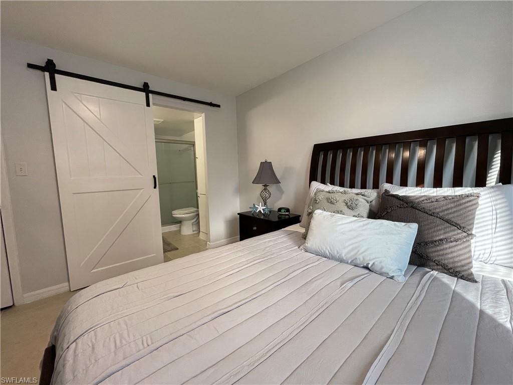 170 Turtle Lake Court, Unit 103 Naples, FL 34105 - Photo 13 of 37 Bedroom featuring ensuite bathroom and a barn door