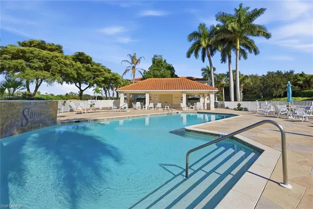 a view of a house with pool lawn chairs under an umbrella