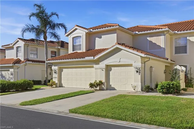 a view of a white house next to a yard and palm trees