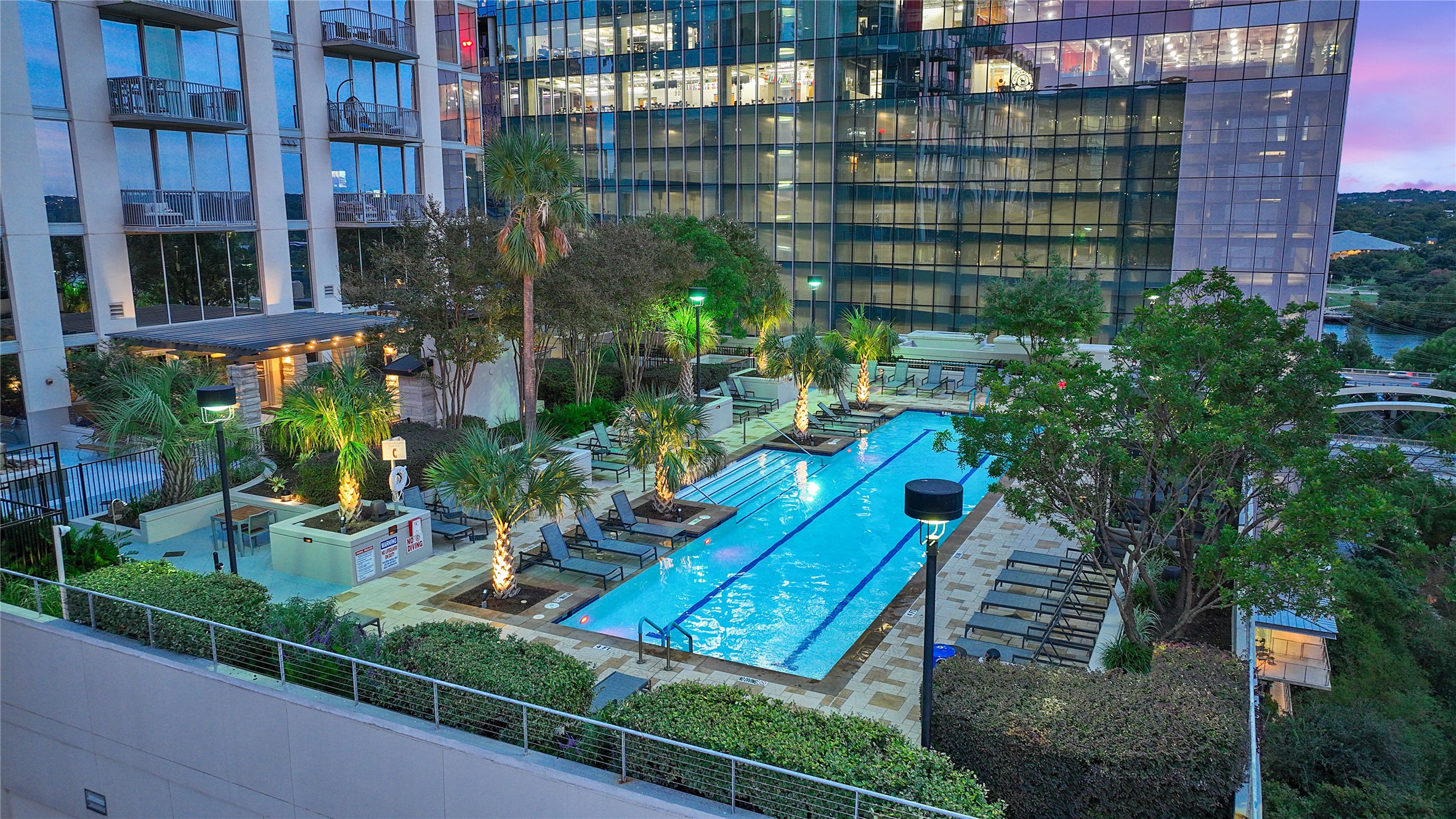360 Nueces Street, Unit 2005 Austin, TX 78701 - Photo 33 of 37 The property features an outdoor swimming pool with lounge chairs, surrounded by lush landscaping and mature palm trees