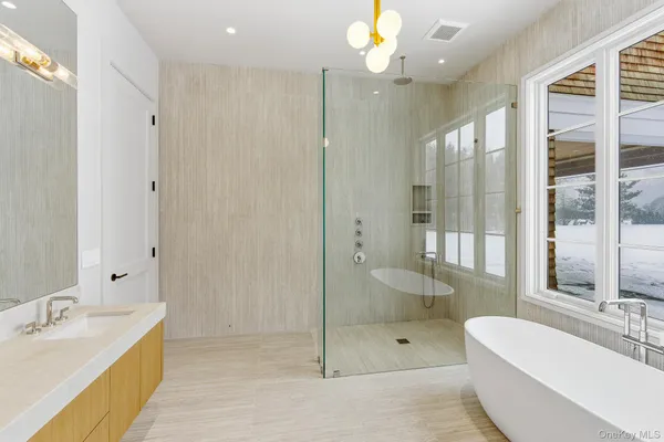 a spacious bathroom with a bathtub shower sink mirror and toilet