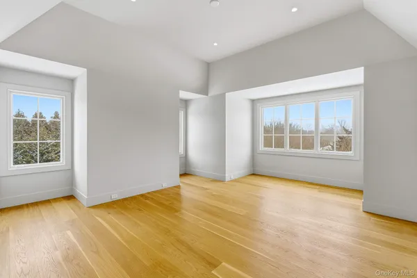 a view of an empty room with a window and wooden floor