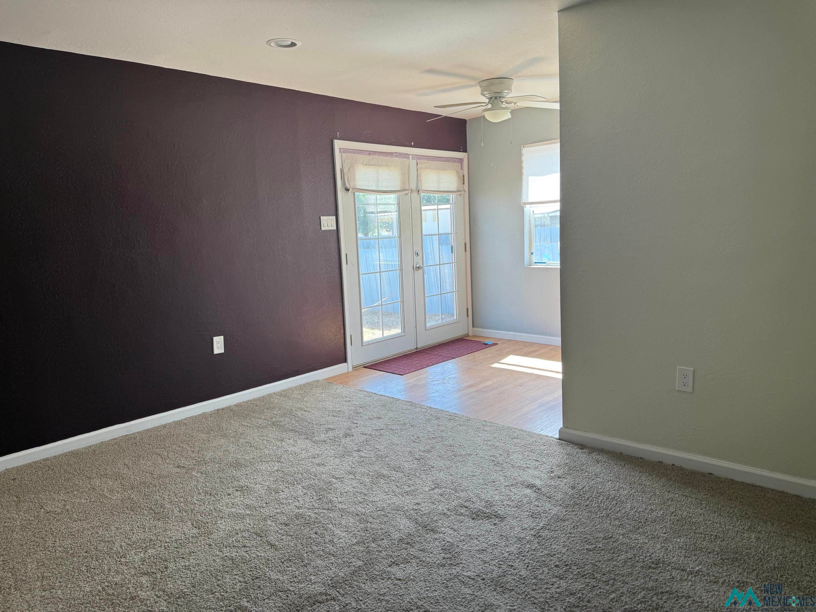 104 Shawnee Road Logan, NM 88426 - Photo 24 of 36 Carpeted flooring extending into a space with wood-finish flooring, featuring French doors and a ceiling fan