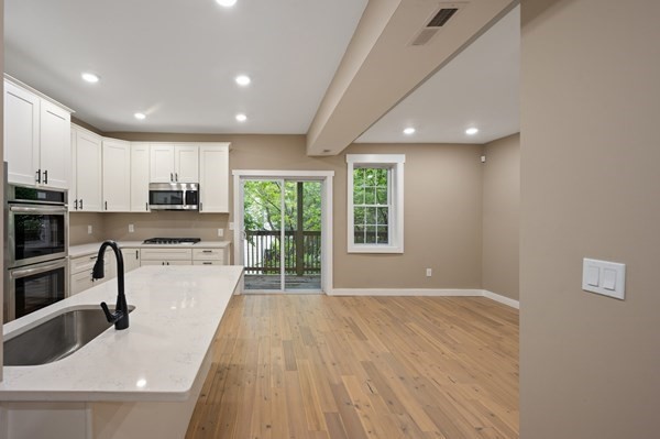5 Monmouth Street Boston, MA 02128 - Photo 24 of 40 a large white kitchen with wooden floors and stainless steel appliances