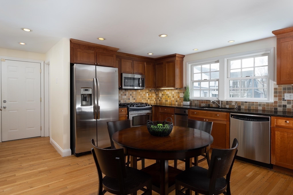 10 Kendall Road Newton, MA 02459 - Photo 7 of 21 a kitchen with stainless steel appliances granite countertop a dining table chairs and a refrigerator