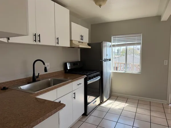 a kitchen with stainless steel appliances granite countertop a stove a sink and a white refrigerator