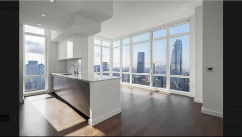 a large white kitchen with wide window and wooden floor