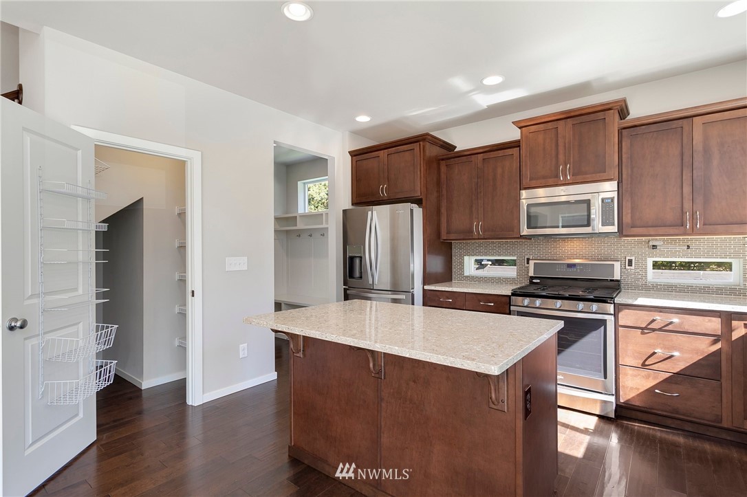 18504 115th Place Southeast Renton, WA 98055 - Photo 11 of 40 a kitchen with stainless steel appliances granite countertop a refrigerator a stove top oven a sink and dishwasher with wooden floor