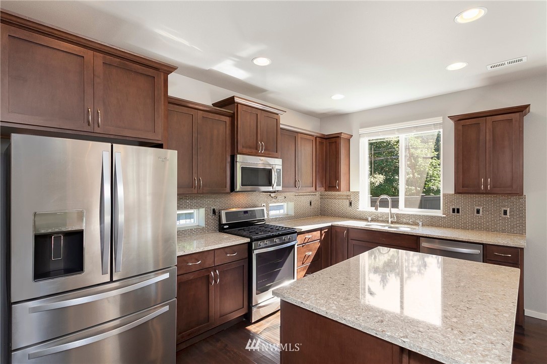 18504 115th Place Southeast Renton, WA 98055 - Photo 13 of 40 a kitchen with stainless steel appliances granite countertop a refrigerator a sink dishwasher a stove and white countertops with wooden floor