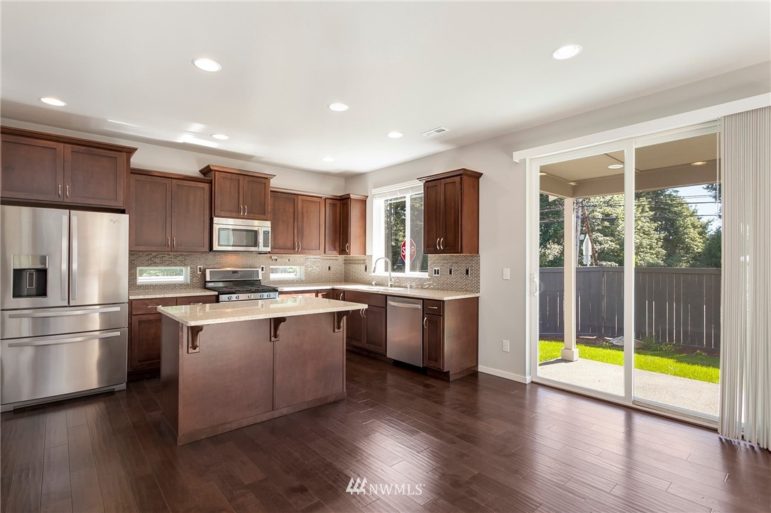 18504 115th Place Southeast Renton, WA 98055 - Photo 8 of 40 a kitchen with stainless steel appliances granite countertop a refrigerator a sink dishwasher a stove and white cabinets with wooden floor