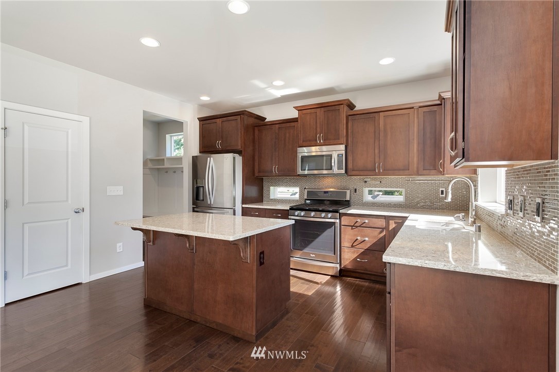 18504 115th Place Southeast Renton, WA 98055 - Photo 10 of 40 a kitchen with stainless steel appliances a sink a stove a refrigerator cabinets and a center island