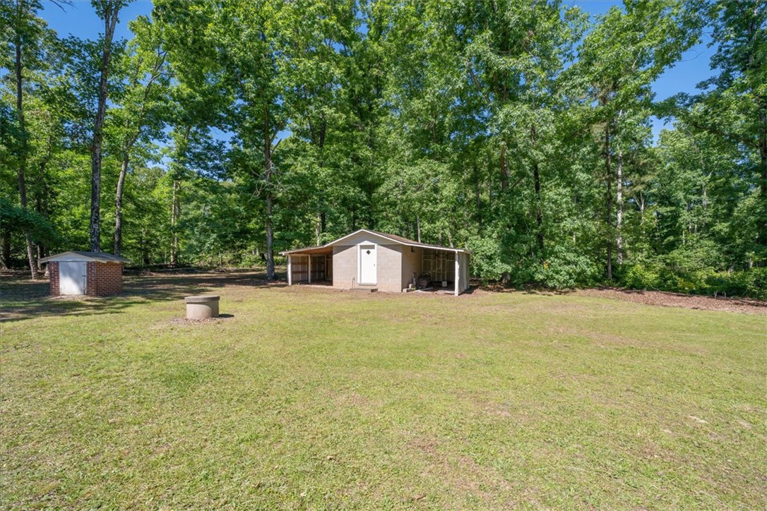 304 Shaw Road Honea Path, SC 29654 - Photo 31 of 39 This expansive yard offers ample space with charming outbuildings, surrounded by a serene treed landscape.