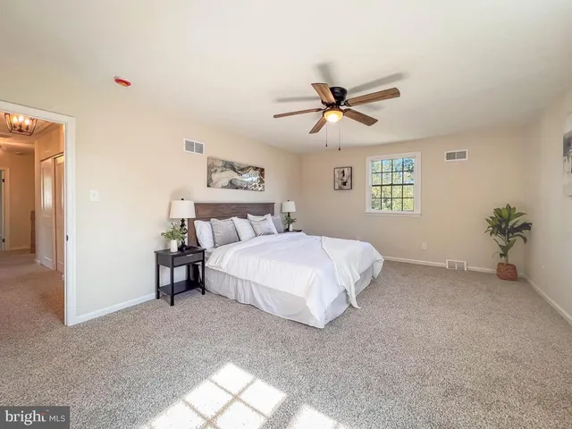 a bedroom with a bed ceiling fan and window