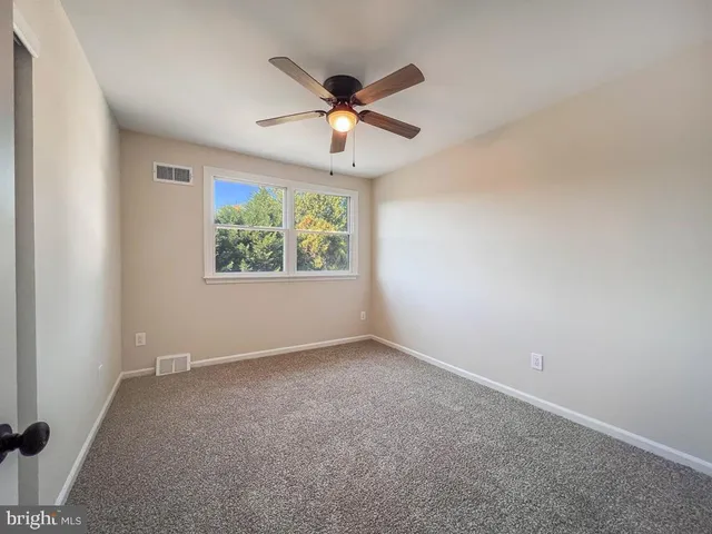 an empty room with a window and a ceiling fan